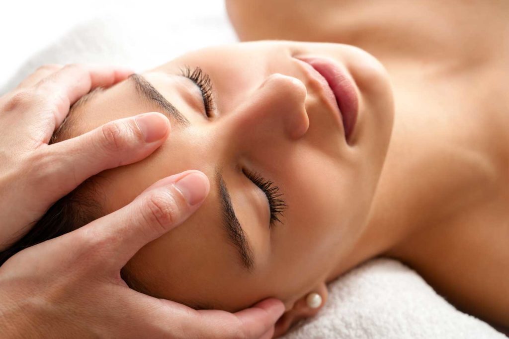 Une femme recevant un massage de réflexologie du visage