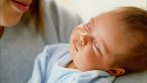 Maman relaxant son bébé avant le coucher avec une routine apaisante.